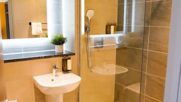 Un baño moderno con ducha de vidrio, lavamanos y espejo.