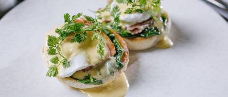 Une assiette avec deux œufs pochés, des épinards et une sauce hollandaise.