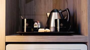 A modern kitchen with a coffee maker, a kettle, and a microwave on a glass shelf. Below, there's a white cabinet with a digital lock.