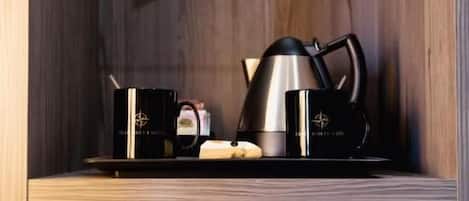 A modern kitchen with a coffee maker, a kettle, and a microwave on a glass shelf. Below, there's a white cabinet with a digital lock.