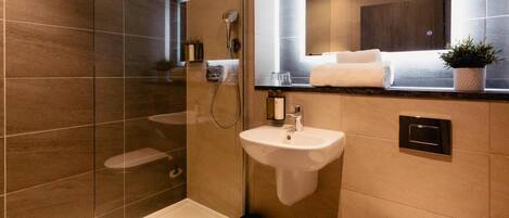 A modern bathroom with a glass-enclosed shower, a pedestal sink, and a toilet.