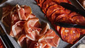 A tray with sliced cured meats, including prosciutto and salami.