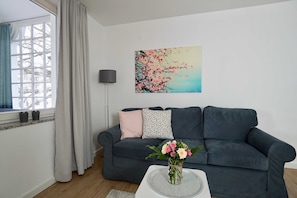 A living room with a dark grey sofa, a white coffee table, and a vase with flowers.