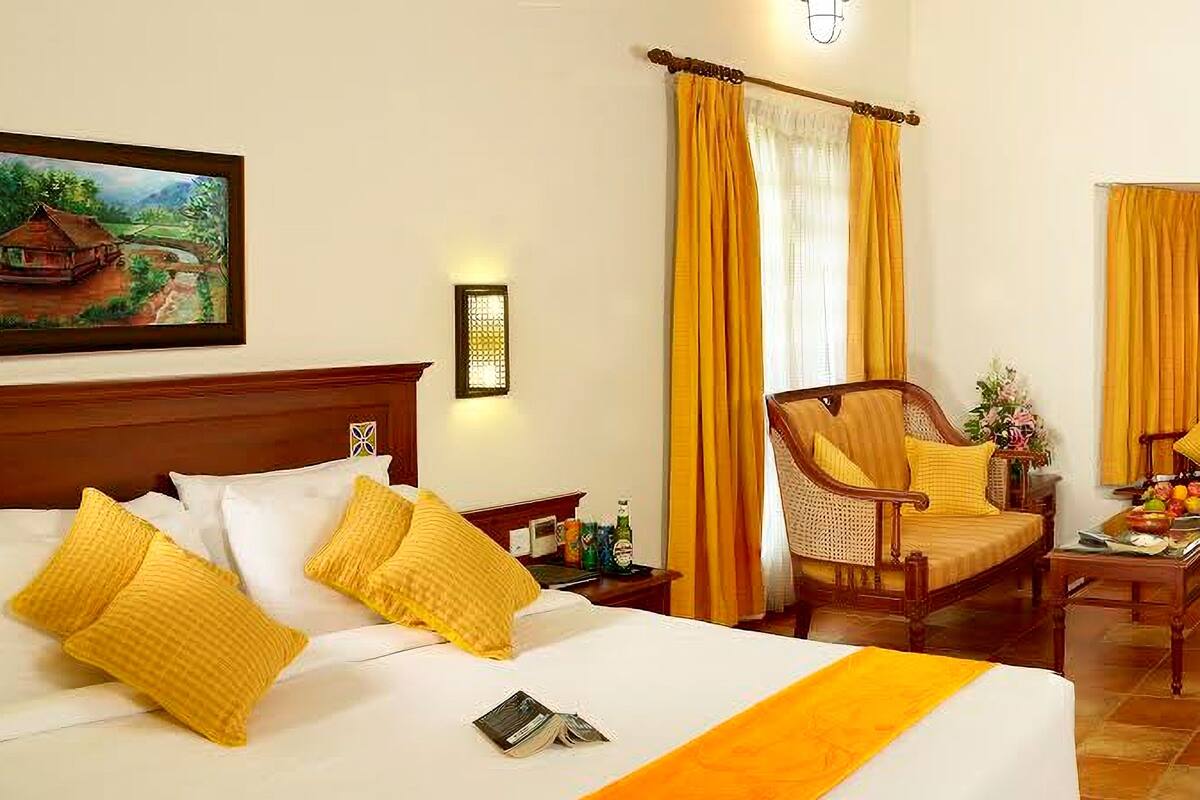A hotel room with a large bed, a wooden headboard, a chair, and a painting on the wall.