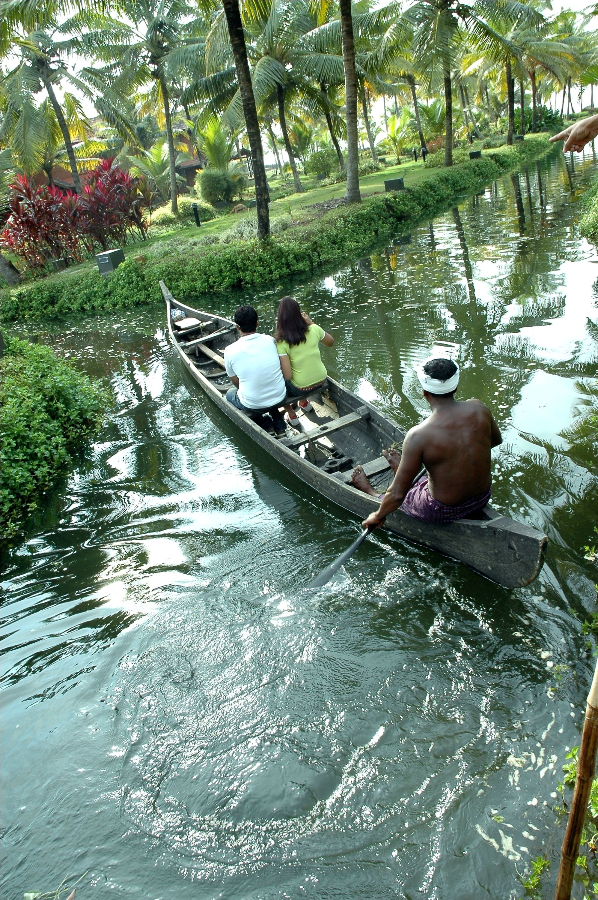 Un canal estrecho con una barca que transporta a tres pasajeros.