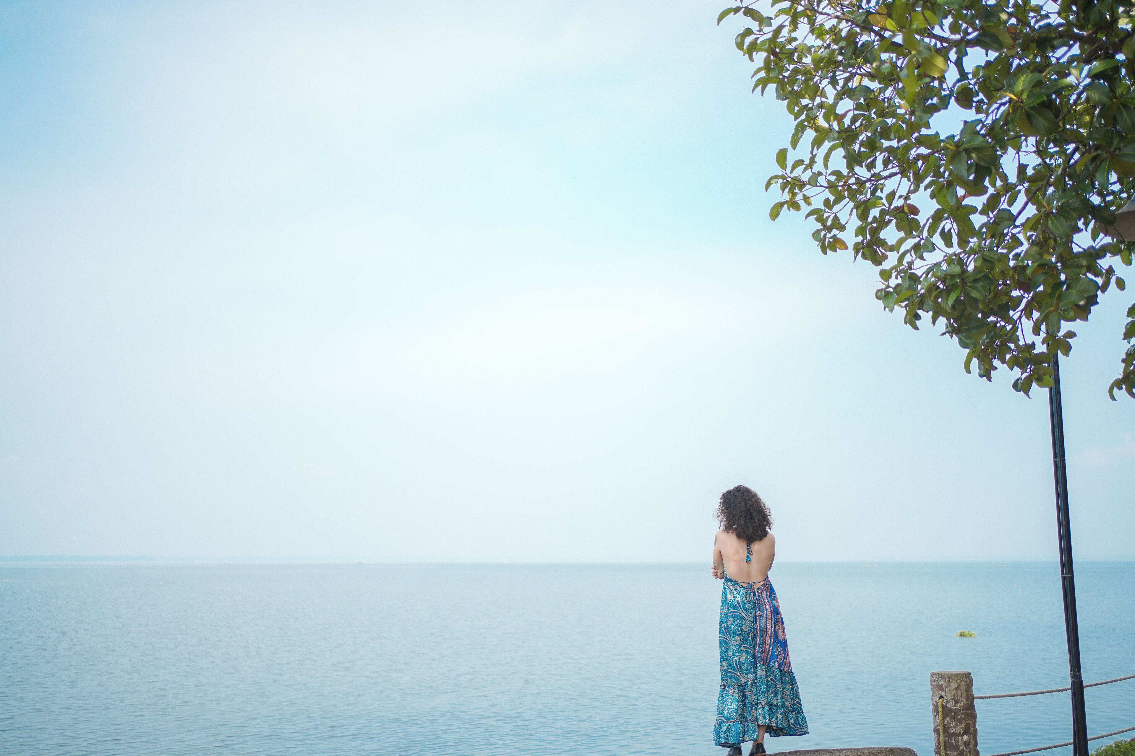 A person standing by a railing overlooking a calm body of water.