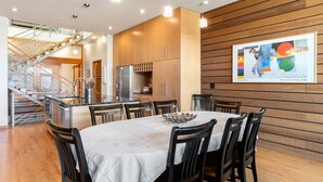 Une cuisine moderne dotée de meubles en bois, d’appareils électroménagers en acier inoxydable et d’un coin repas avec une table et des chaises.