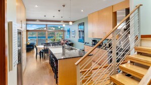 Une cuisine moderne avec des meubles en bois, un îlot central et une vue sur l’extérieur.
