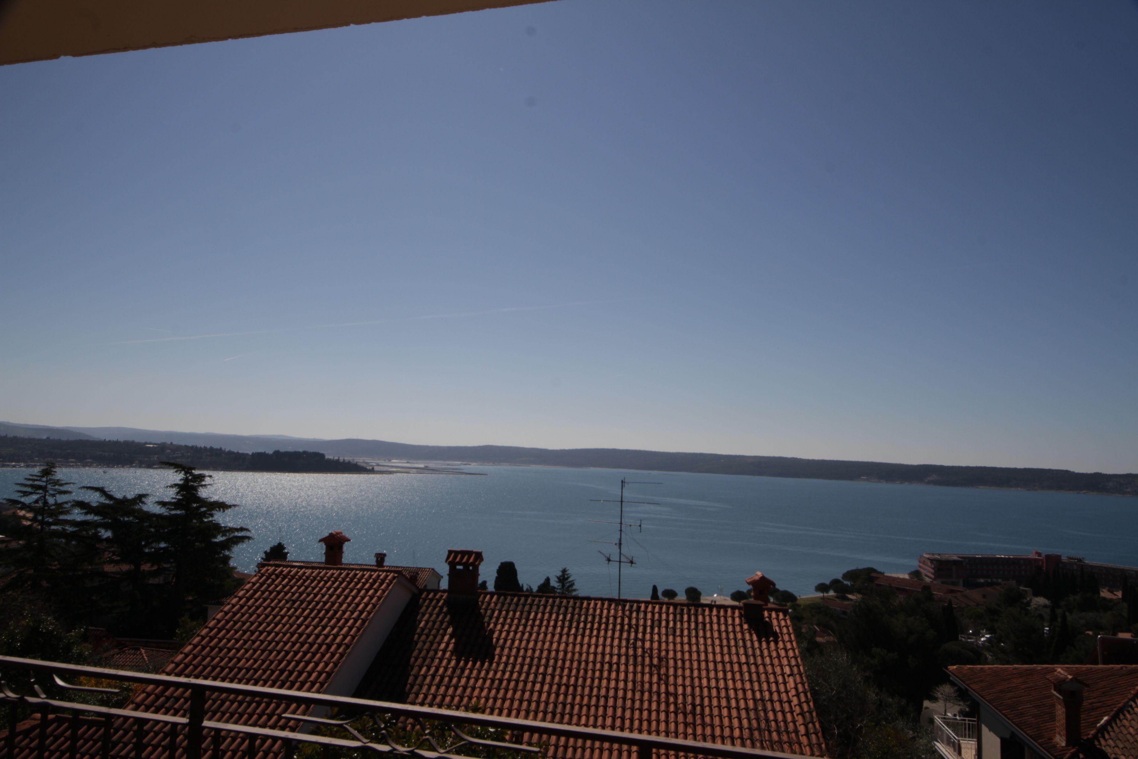 A view of a lake with a clear sky, surrounded by buildings with red-tiled roofs.