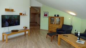A living room with a television, wooden furniture, a cabinet, and a sofa. - An der Pappelwende - five-room apartment type H5 (Karlshagen)