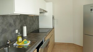 A modern kitchen with a stainless steel sink, a built-in oven, and a refrigerator. - An der Pappelwende - five-room apartment type H5 (Karlshagen)