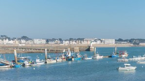 A marina with various boats docked, a bridge in the background, and buildings along the shore. - Apartment Hoédic by Interhome (Quiberon)