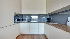 Una cocina moderna con armarios blancos, encimera de madera y vistas de la ciudad a través de un ventanal.