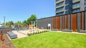 Un edificio moderno con techo plano, patio cubierto de césped y zona de juegos.