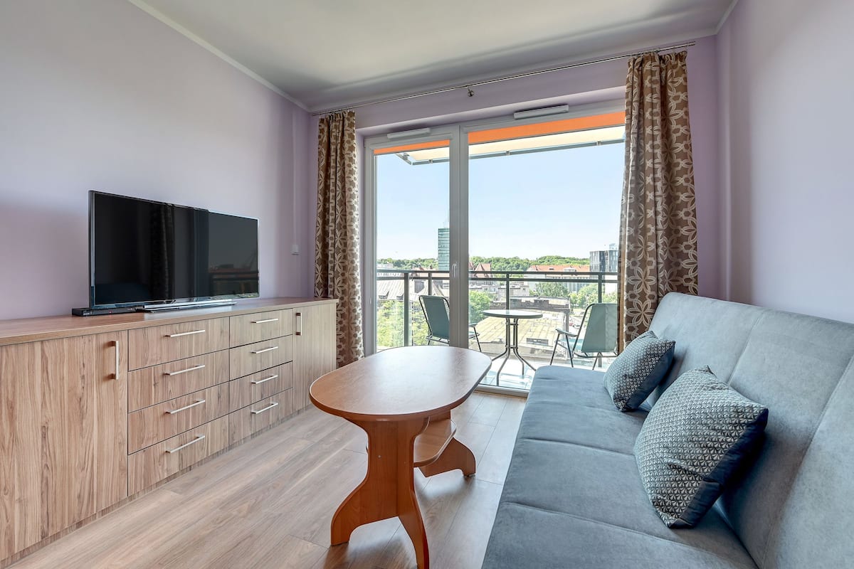 Ein modernes Wohnzimmer mit einer Couch, einem Holzkasten und einem Fernseher.