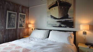 A neatly made bed with white linens, a wooden headboard, and two wall-mounted lamps.