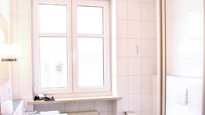 A bathroom with a white sink, a toilet, and a shower area. - Single Room 2 - Hotel Garni Goldener Schwan (Bad Windsheim)