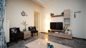 A modern living room with a flat-screen TV, a wooden coffee table, and a sofa with decorative pillows. - Blue Ark Athenian Nest (Nea Smirni)