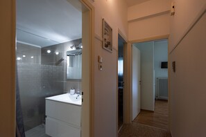 A modern bathroom with a glass shower enclosure, a white sink, and a mirror. - Blue Ark Athenian Nest (Nea Smirni)