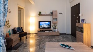 A modern living room with a flat-screen TV, wooden furniture, and a marble floor. - Blue Ark Athenian Nest (Nea Smirni)