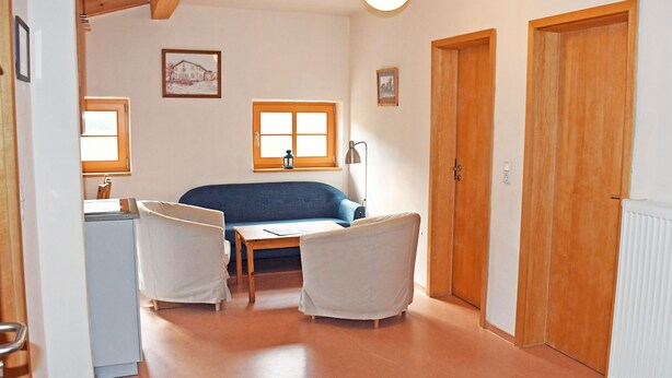A room with a sofa, two chairs, a table, a window, and a door. - 05 Holiday apartment Leberblümchen - Haus am Höft in Gager with lake view and sauna (Gager)