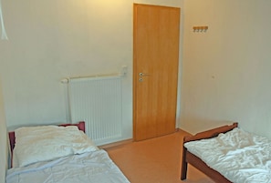 A room with two single beds, a wooden door, a radiator, and a wall-mounted light fixture. - 05 Holiday apartment Leberblümchen - Haus am Höft in Gager with lake view and sauna (Gager)