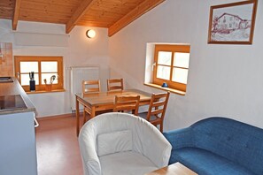 A cozy room with a dining table, chairs, a sofa, a radiator, and a window with a view.