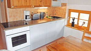 A kitchen with wooden cabinets, a built-in oven, a coffee maker, and a window with a view. - 05 Holiday apartment Leberblümchen - Haus am Höft in Gager with lake view and sauna (Gager)