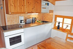 Una cocina con armarios de madera, horno empotrado, cafetera y ventana con vistas.