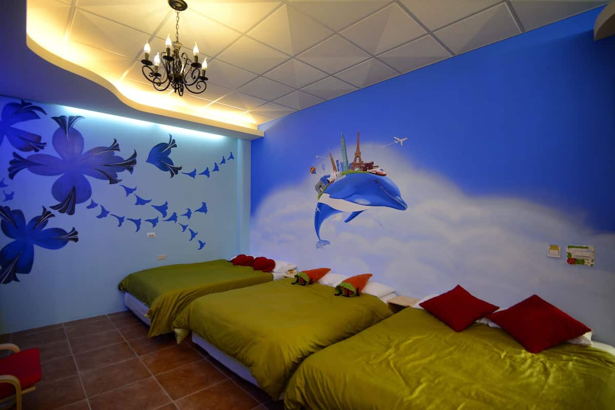 A room with two beds, a chandelier, and a mural of a dolphin carrying a cityscape.