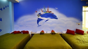 A room with two beds, each with green bedding and red pillows. A large mural of a whale with various landmarks is on the wall. - Kenting Bay Homestay III (Hengchun)