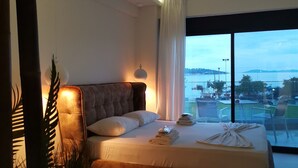 Et moderne hotelværelse med en stor seng, havudsigt og en balkon med udendørs møbler.