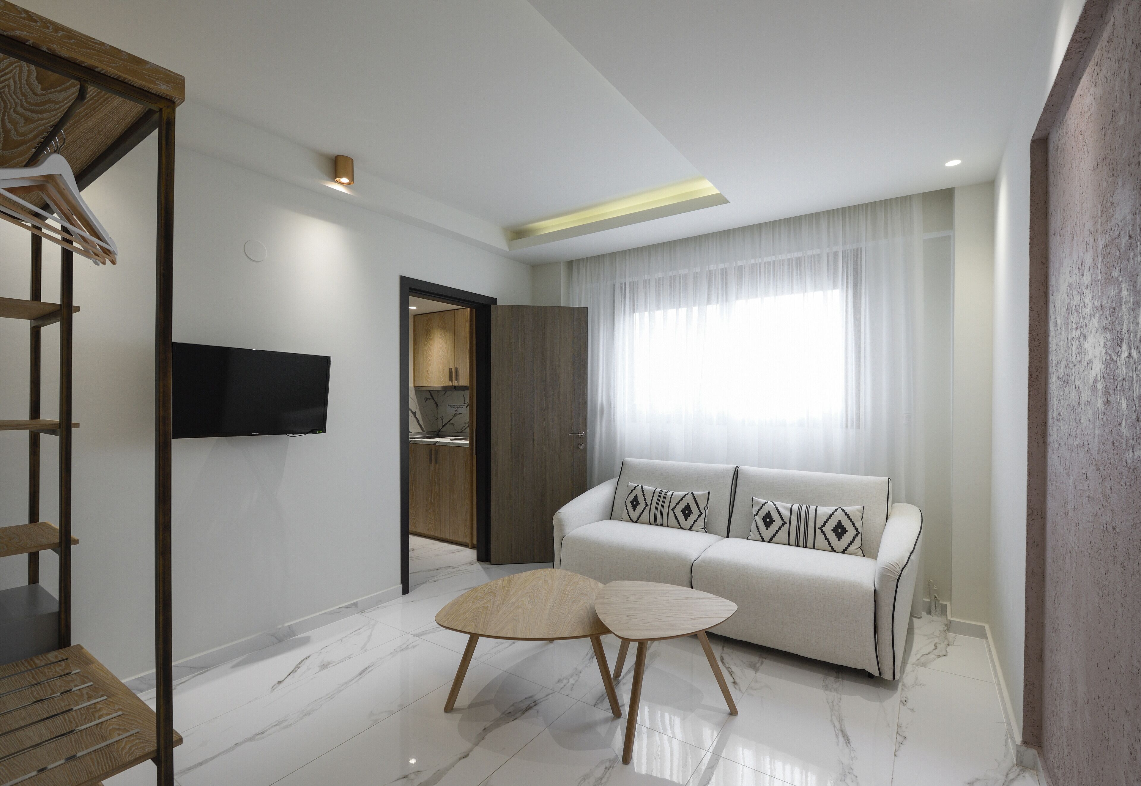 Een moderne woonkamer met een bank, twee bijzettafels, een televisie en een houten plank.