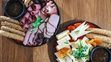 Two charcuterie boards with various meats, cheeses, and crackers.