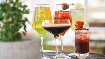 Quatro cocktails diferentes em copos diversos sobre uma mesa.