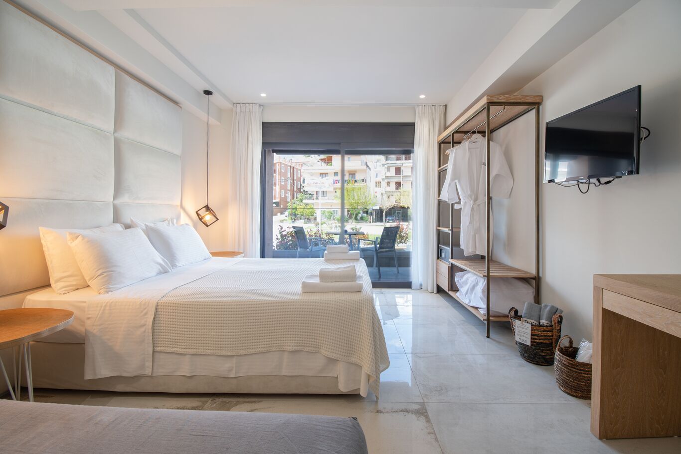 Una habitación de hotel con cama, escritorio, televisor y vistas al exterior.