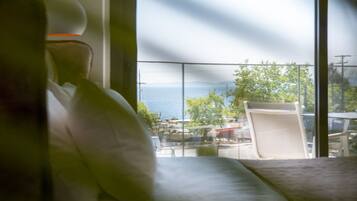 Ein Balkon mit Meerblick, ein weißer Stuhl und ein Tisch.
