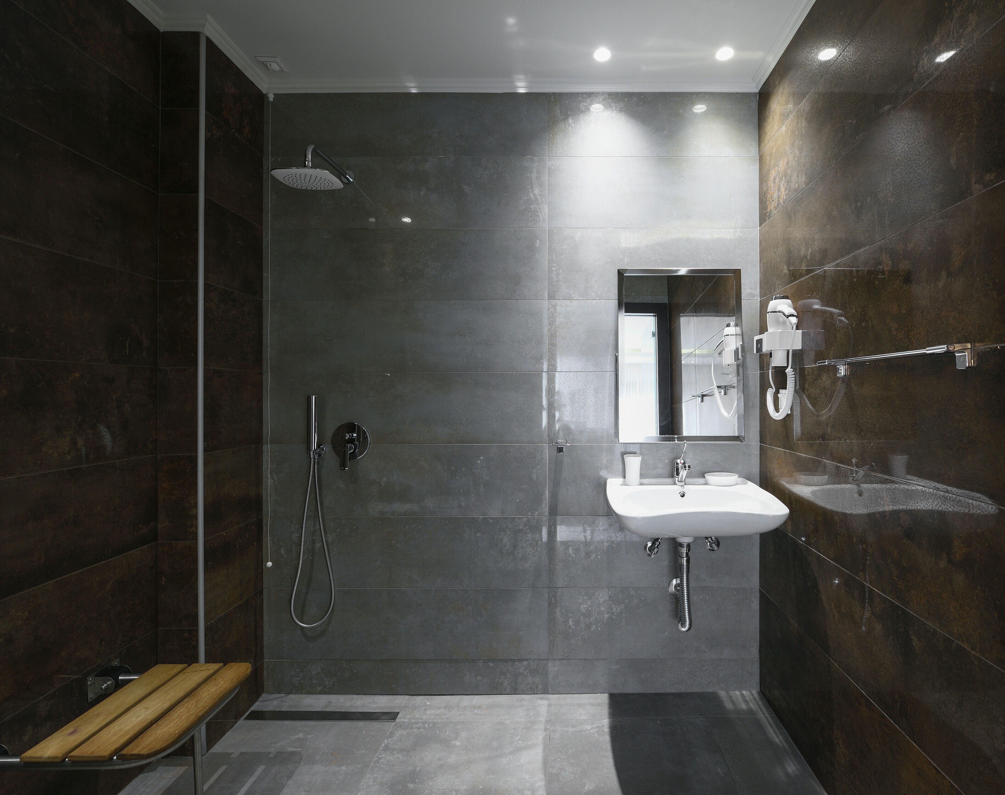 A modern bathroom with a shower, a sink, and a bench.