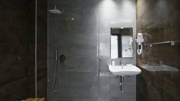 A modern bathroom with a shower, a sink, and a bench.