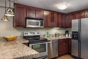 A kitchen with wooden cabinets, a stainless steel refrigerator, a microwave, a stove, and a dishwasher. - Terracehouse 93 - Steps to Slopes | Inviting Mountain Retreat, Pool & Hot Tub (Snowmass Village)