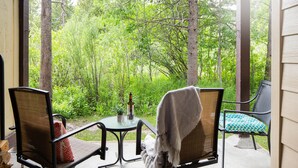 Een terras met twee stoelen, een tafel en een fles wijn.