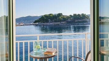 A balcony with a table and chairs, overlooking a body of water and a distant shoreline.