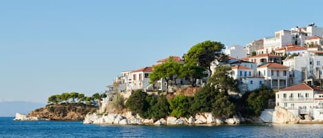 A coastal village with white buildings and red roofs, situated on a rocky outcrop with a view of the sea.