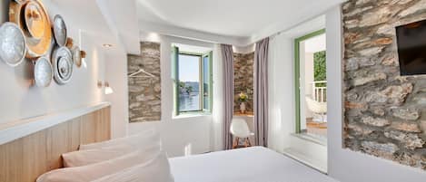 A modern hotel room with a large bed, a stone wall, a view of the outdoors, and a decorative metal wall art piece.