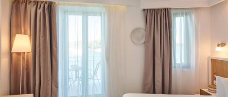 A hotel room with a bed, a chair, a table, and curtains.