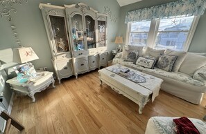 Cozy living room with a large cabinet, comfortable sofa, and warm wooden flooring.