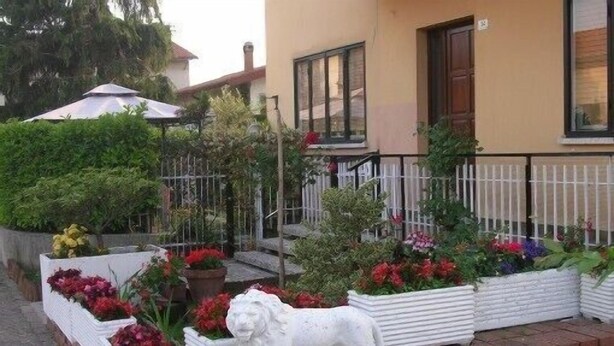 Un jardin avec des parterres de fleurs et une statue de lion blanc.