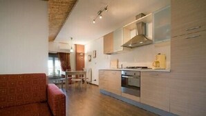 Une cuisine compacte dotée d’appareils électroménagers modernes, un coin repas avec une table et des chaises, et un canapé à motifs.