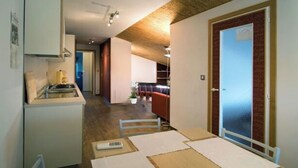 Une cuisine compacte comprenant une cuisinière, une table à manger avec une chaise, et une porte donnant sur un espace de vie.