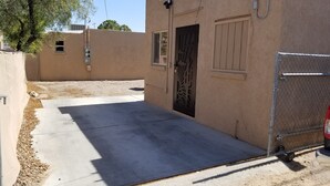 A building with a concrete driveway leading to a door with a decorative metal gate. - A Gem in the Heart of Tucson (Tucson)